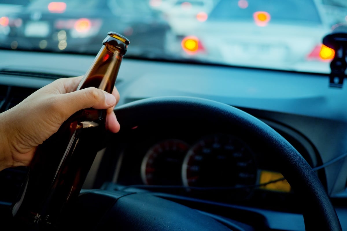 Man drink beer while driving car. Driving in a state of intoxication.