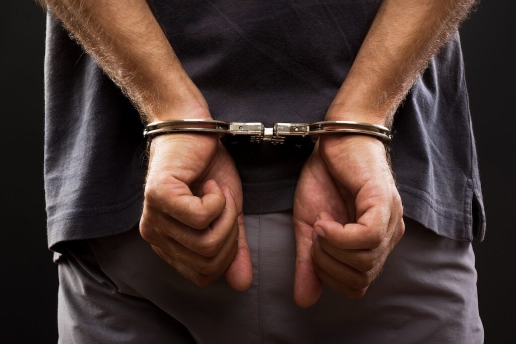 Close-up. Arrested man handcuffed hands at the back