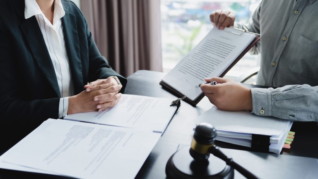 Lawyer signing legal document with Judges gavel on table