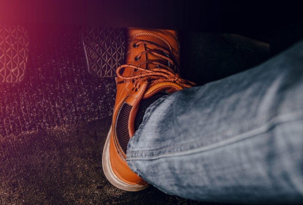 Leg pressing the gas pedal. Concept of car acceleration, reckless driving.