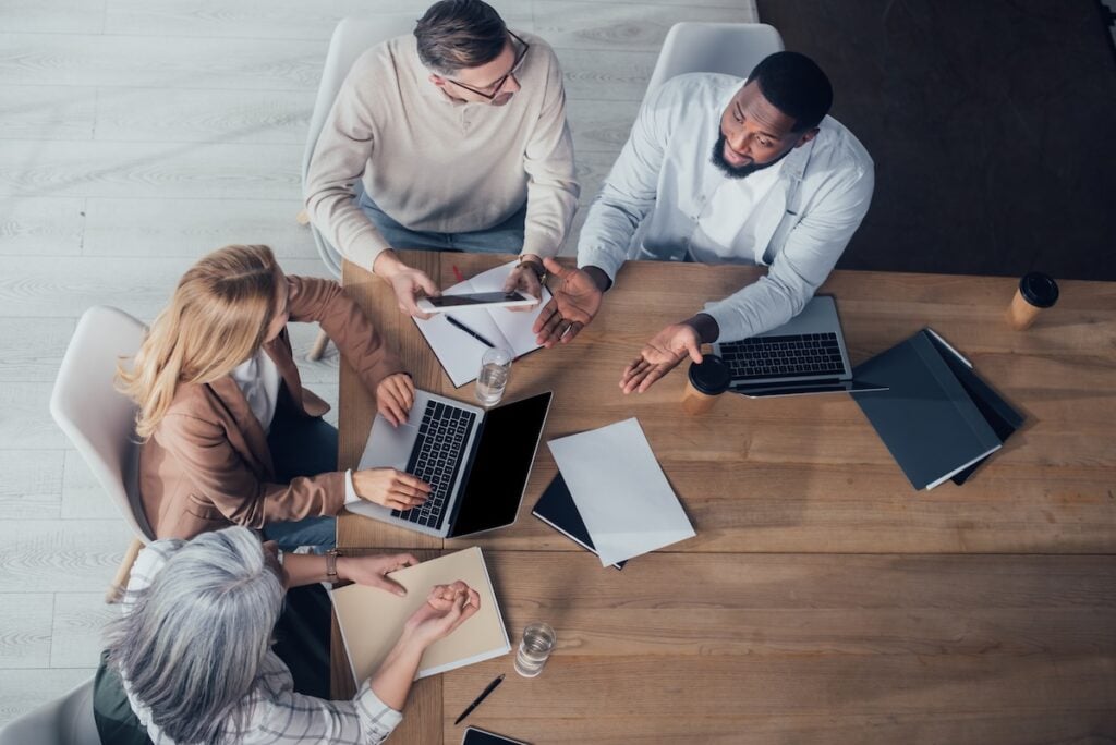 overhead view of colleagues talking and sitting at table during meeting